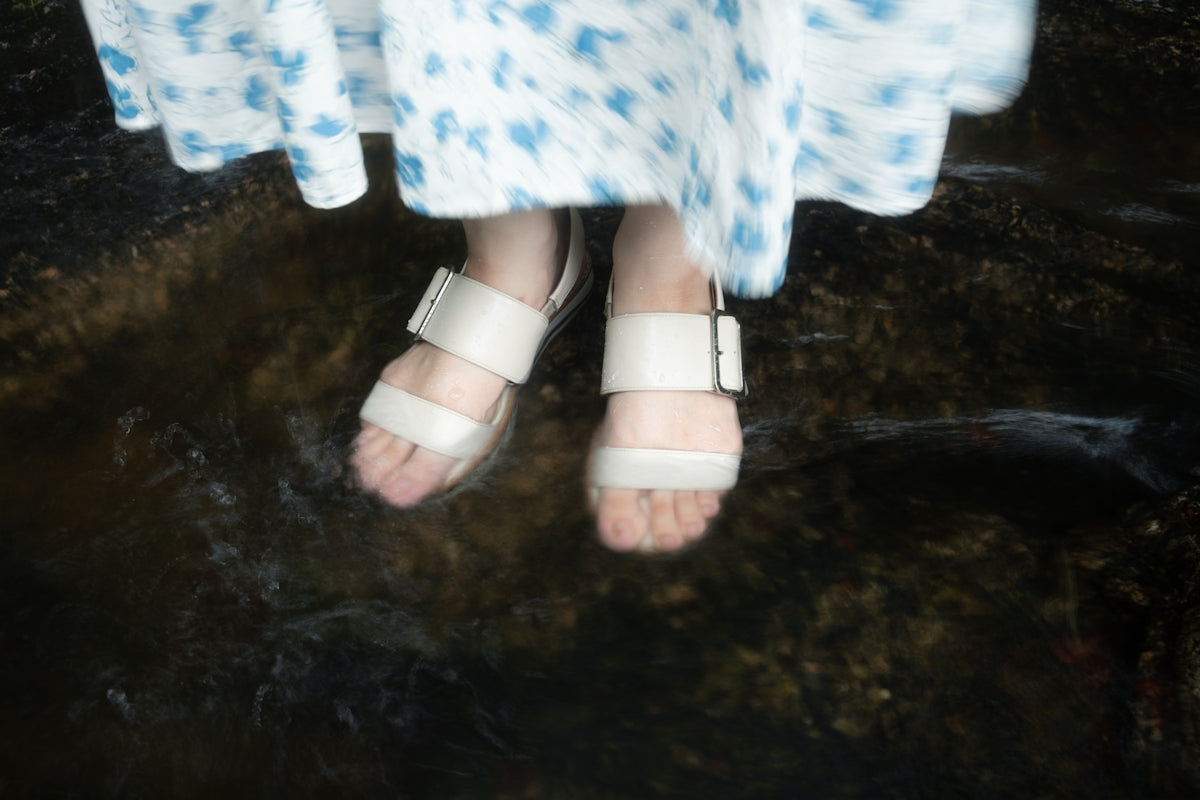 Feet in sandals are wading in water.