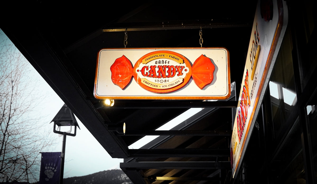 An illuminated candy store sign shaped like a wrapper.