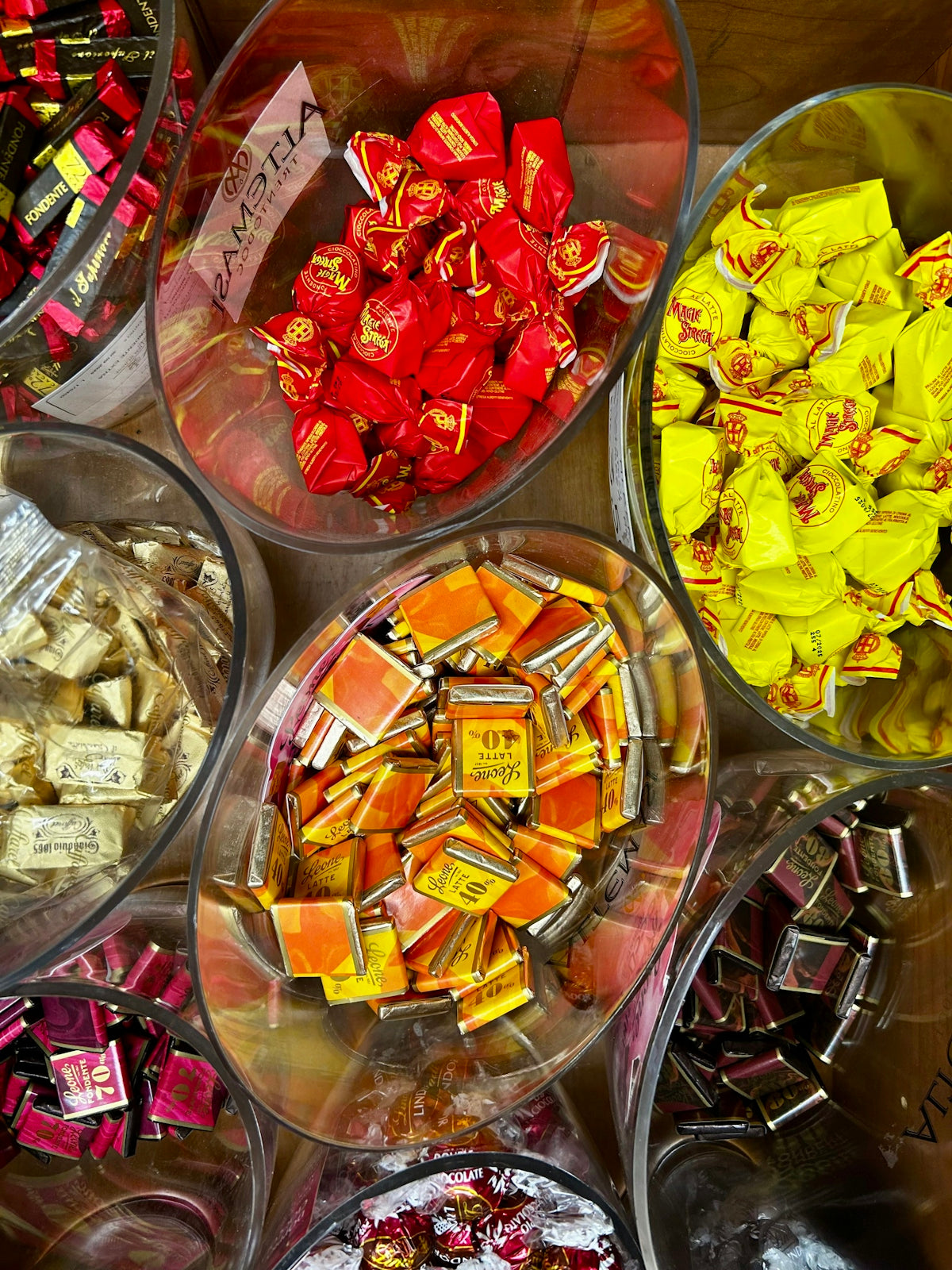Glass bowls filled with various colorful wrapped chocolates in a candy shop