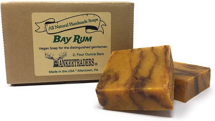 A boxed set of two all natural, vegan bay rum bar soaps with the brand name YANKEETRADERS visible on the packaging. The soaps are beige with a swirl pattern and have a label indicating the scent as bay rum.