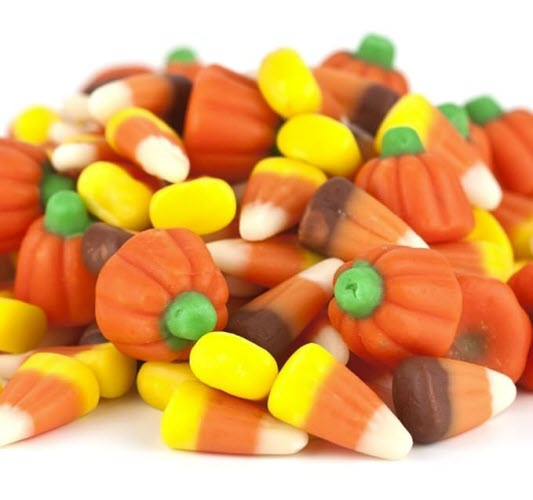 A pile of Halloween candy corn and pumpkin-shaped candies in various colors, including orange, yellow, brown, and green.