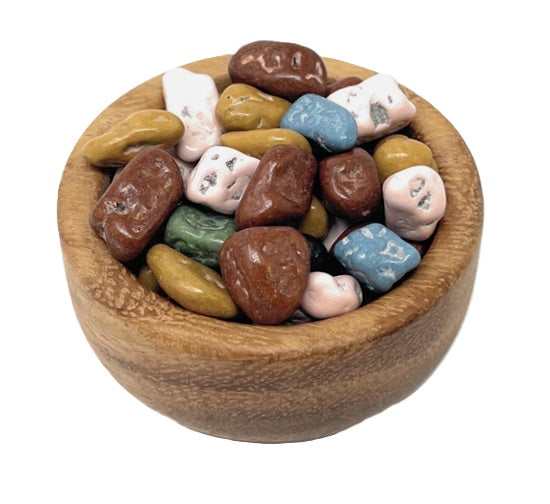 Wooden bowl filled with multicolored chocolate rocks candy on a white background