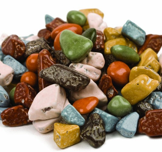 A pile of chocolate shaped rock candy in various colors including green, red, brown, blue, and yellow.