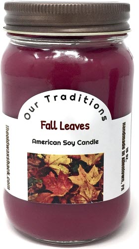 A burgundy-colored soy candle in a mason jar with a label reading 'Fall Leaves American Soy Candle' and leaves pictured below.