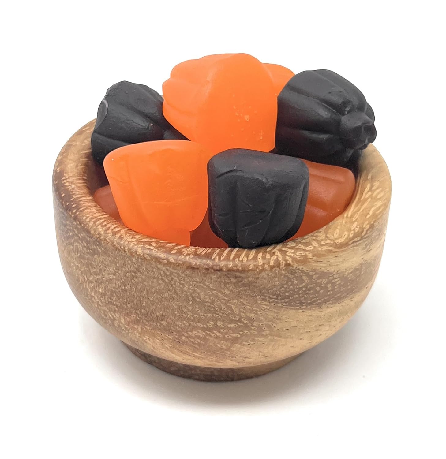 Wooden bowl with orange and black Ju Ju Pumpkins on a white background