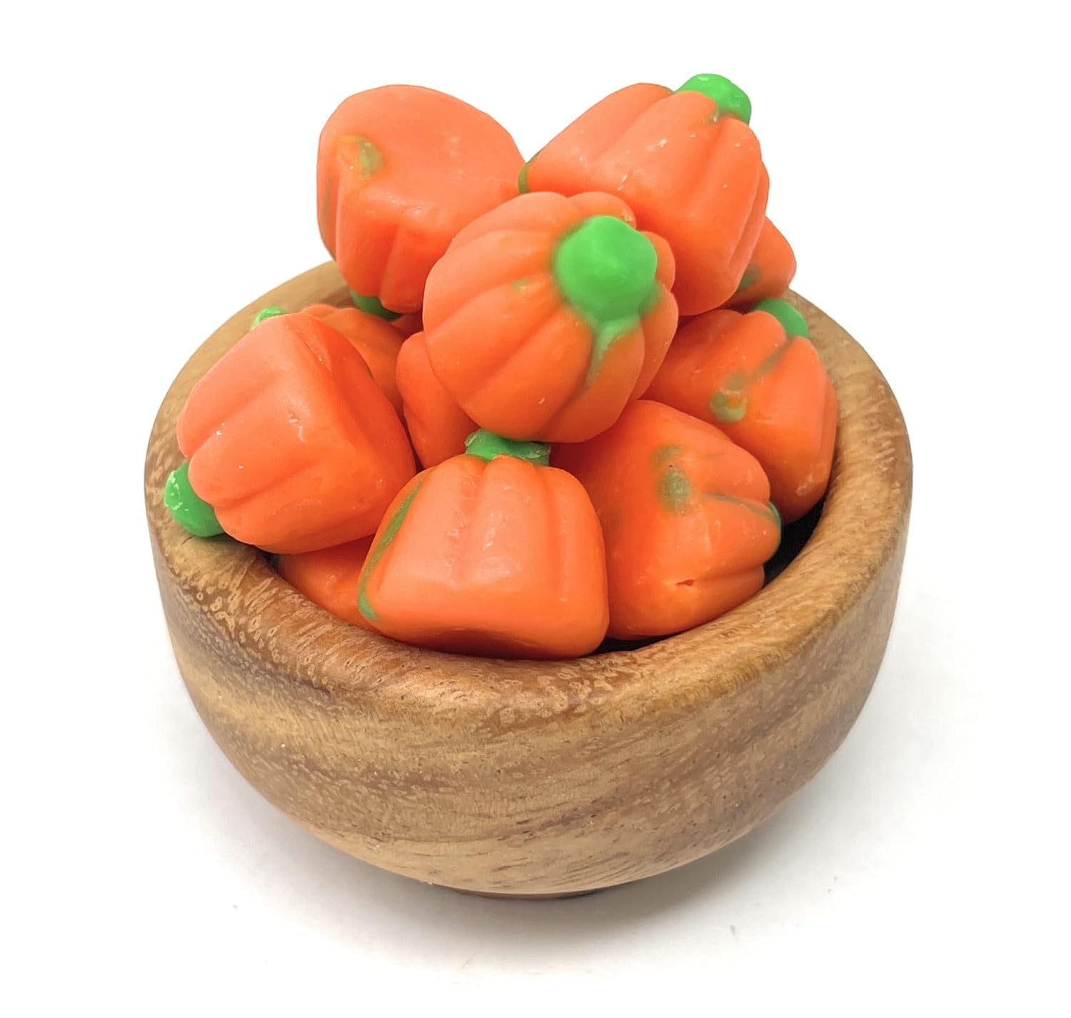 Wooden bowl filled with orange Mello pumpkin-shaped candies on a white background