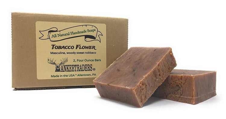Two bars of Tobacco Flower soap next to their packaging, labeled as handmade with all natural ingredients suitable for men.